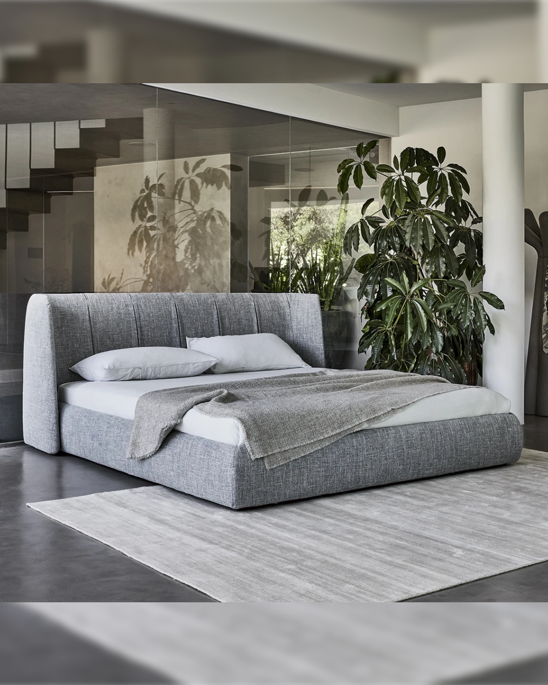 Angled room view of Velglade bed with tall curved headboard and floor base